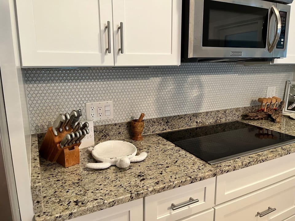 Granite counters and penny tile backsplash. Electric cook top with wall oven