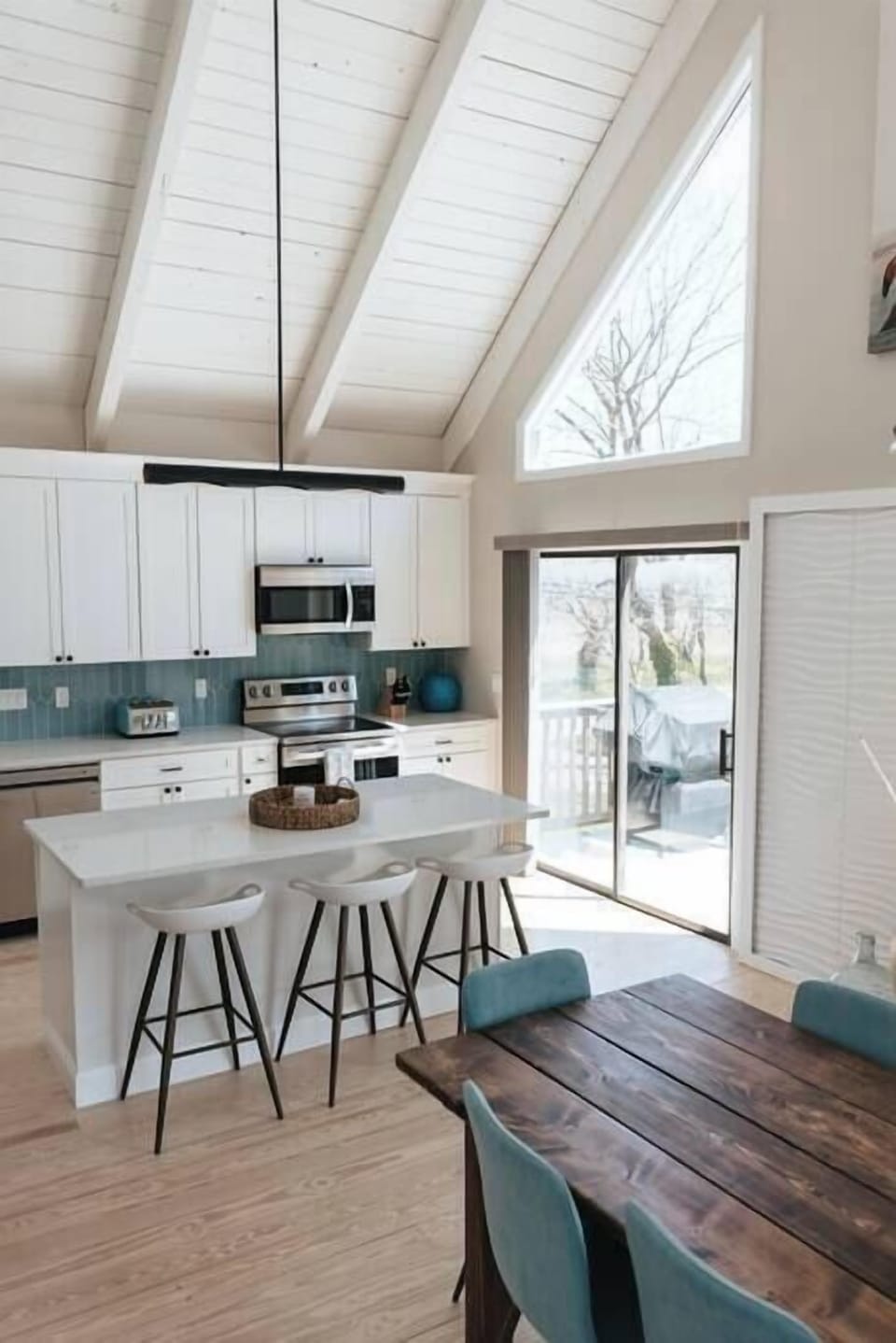 Main house view of chefs kitchen and island. Sliders lead out to wrap around deck with more dining!