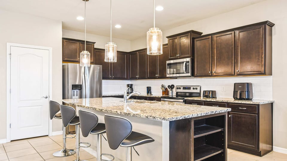 Modern gourmet kitchen with sleek granite counters, stylish lighting & seating!