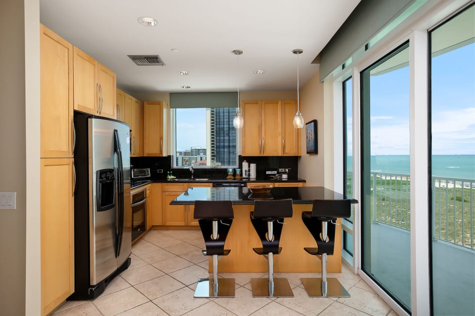 Fully equipped kitchen with stainless steel appliances and breakfast bar seating with Gulf views.