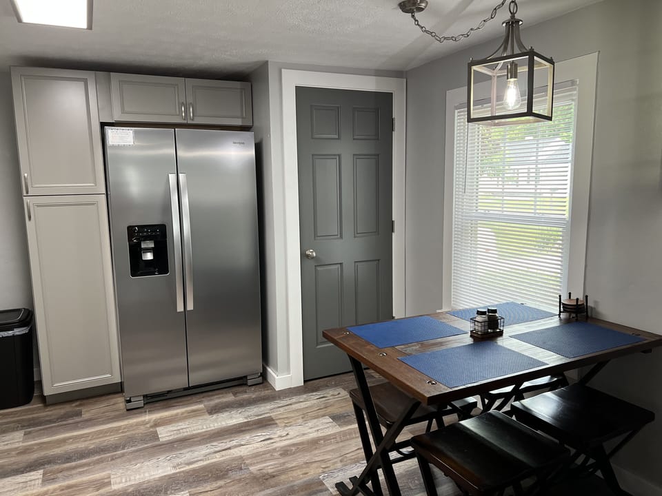 Kitchen area with new stainless refrigerator and dining table for four