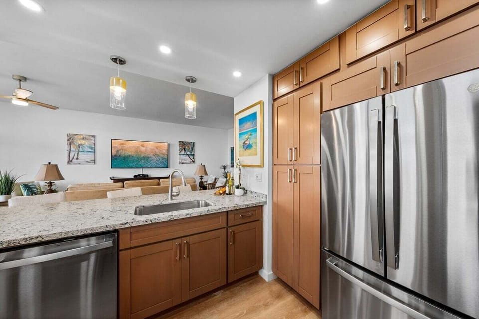 Fully remodeled kitchen with stainless refrigerator, modern cabinetry, and ample counter space for convenient island cooking.