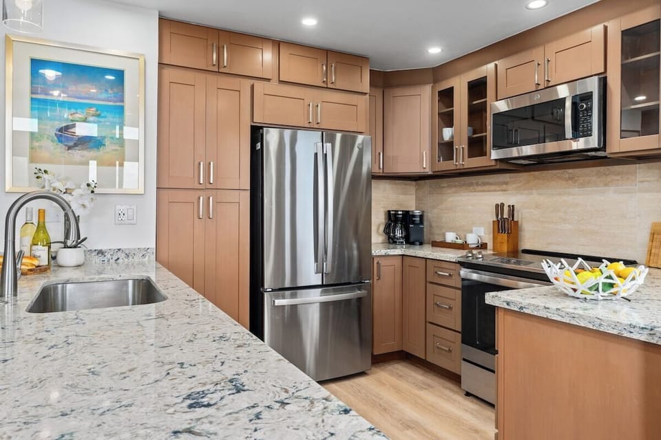 Remodeled gourmet kitchen with stainless appliances, wine fridge, air fryer, granite counters, and full amenities for effortless island dining.