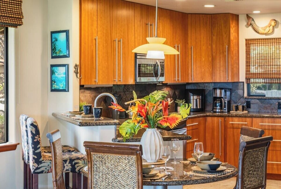 Fully equipped kitchen with warm wood cabinetry, stainless steel appliances, and tropical floral accents for a welcoming island vibe.