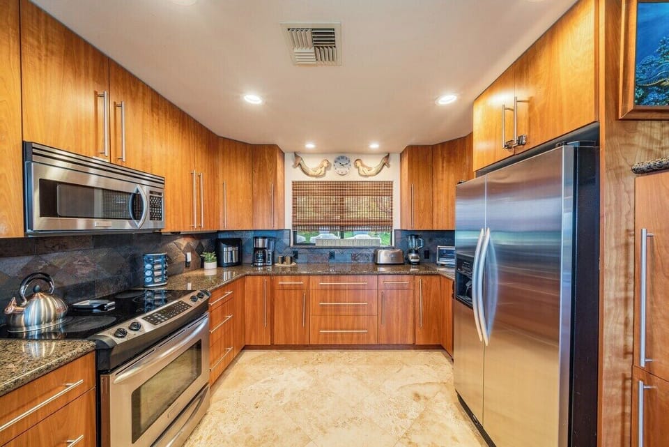 Modern kitchen with stainless steel appliances, granite countertops, and ample cabinetry, ideal for preparing home-cooked meals during your stay.