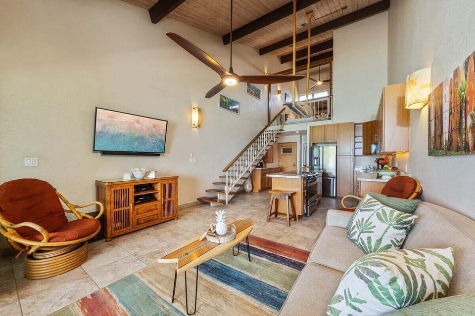 Inviting living area with vaulted ceilings, lanai access, and ocean backdrop.