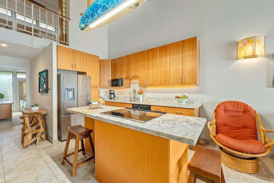 Remodeled kitchen with full appliances, bar seating, and bright coastal style.