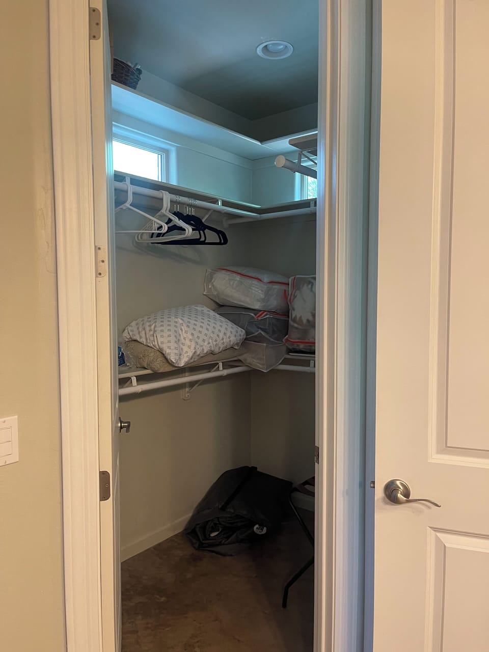 Walk in closet with extra linens and luggage trays.
