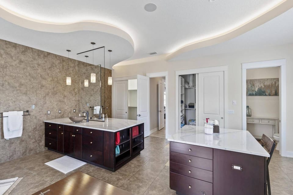 Luxurious Massive Master Bath featuring Dual Vanities, a Soaking Tub, a Spacious Walk-In Shower, Dual Closets, and Access to the Front Balcony.