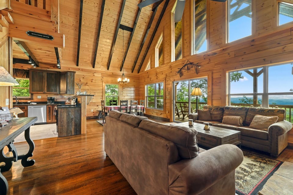 Spacious great room connecting the living area and kitchen with exposed wood beams, hardwood floors, and expansive windows overlooking the surrounding mountains. Located near Bryson City for a scenic Smoky Mountains escape.