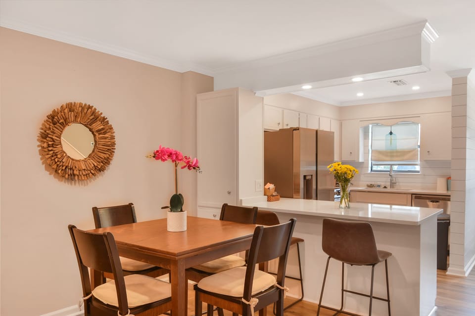 Kitchen and Dining Area - Dining table and island seating beside the remodeled kitchen with quartz counters and pendant lighting.