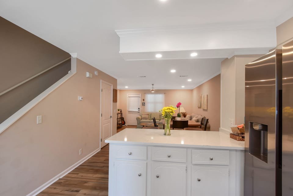 Open Kitchen to Living Room - Open kitchen view showing the island, dining area, living room, stainless appliances, and staircase.