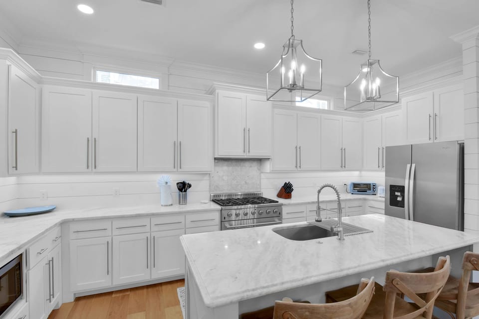 Kitchen with Gas Range and Island - White cabinetry, stainless appliances, five-burner gas range, deep sink, and island seating for meals at the house.