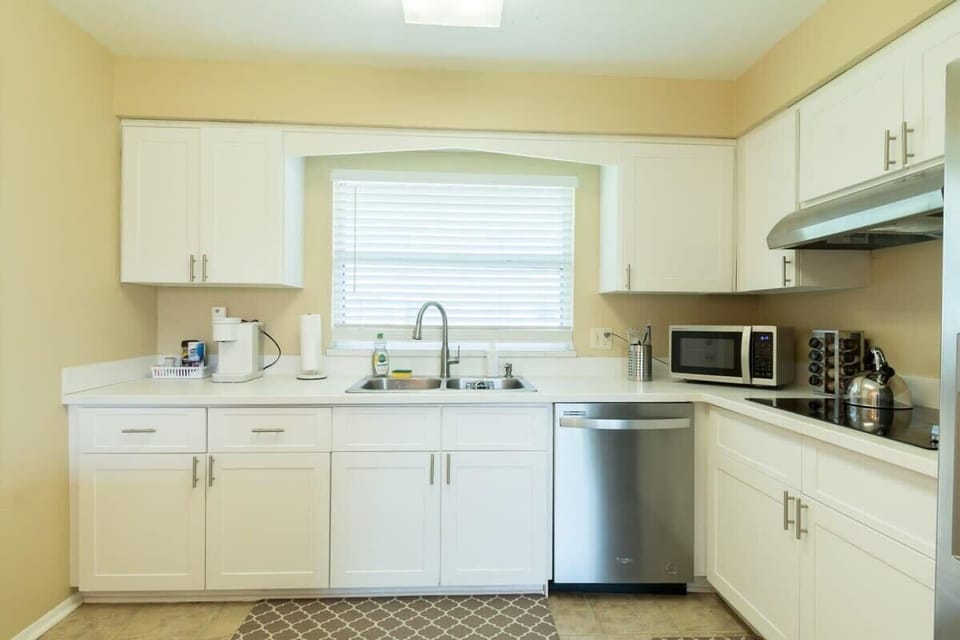 Bright kitchen with white cabinetry and stainless steel appliances