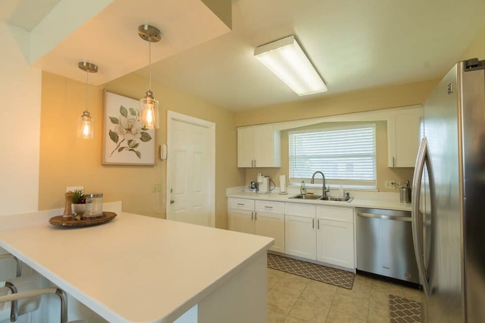 Modern kitchen with white cabinetry, stainless steel appliances, and a breakfast bar with pendant lighting.