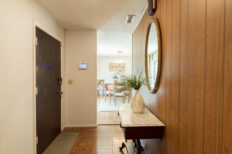 Entryway with wood paneling and a decorative mirror leading to the dining area