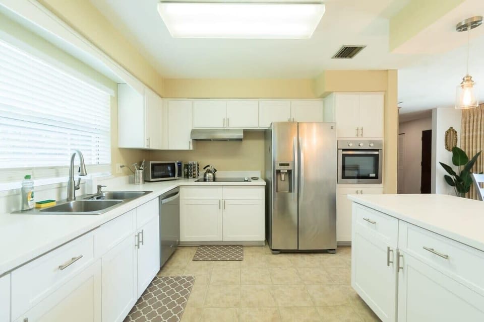 Bright kitchen with white cabinetry and stainless steel appliances