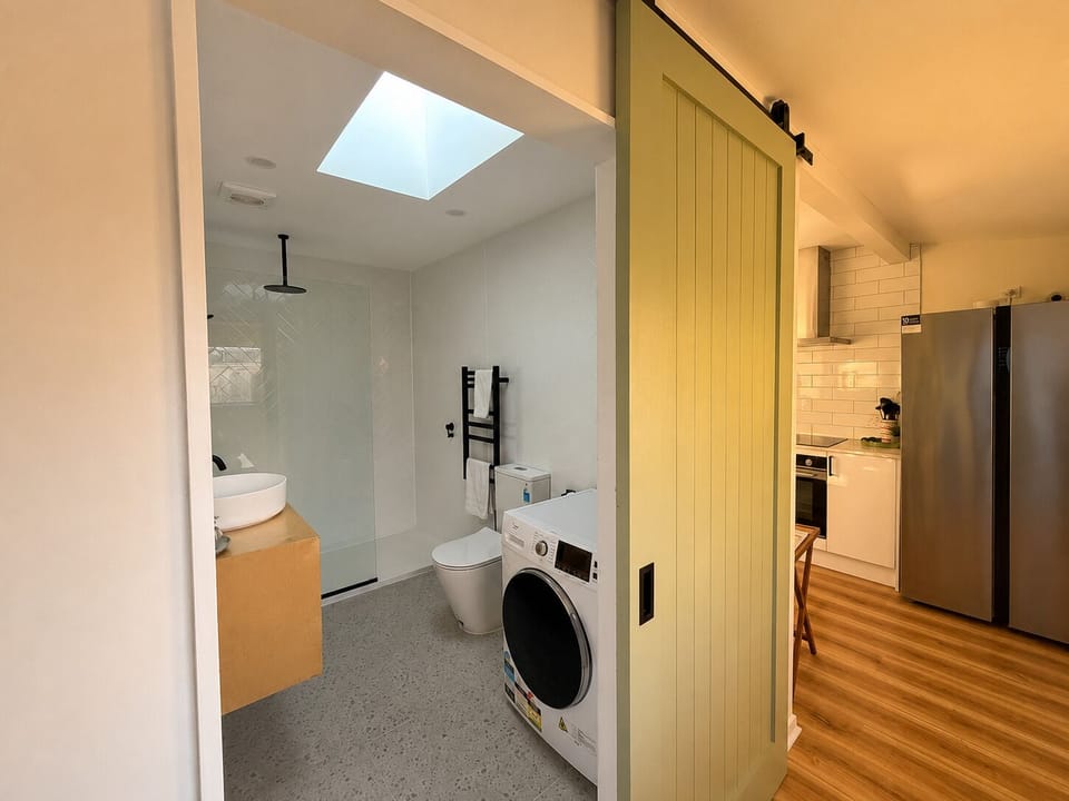 Bright modern bath with skylight, walk-in shower, and in-unit washer
