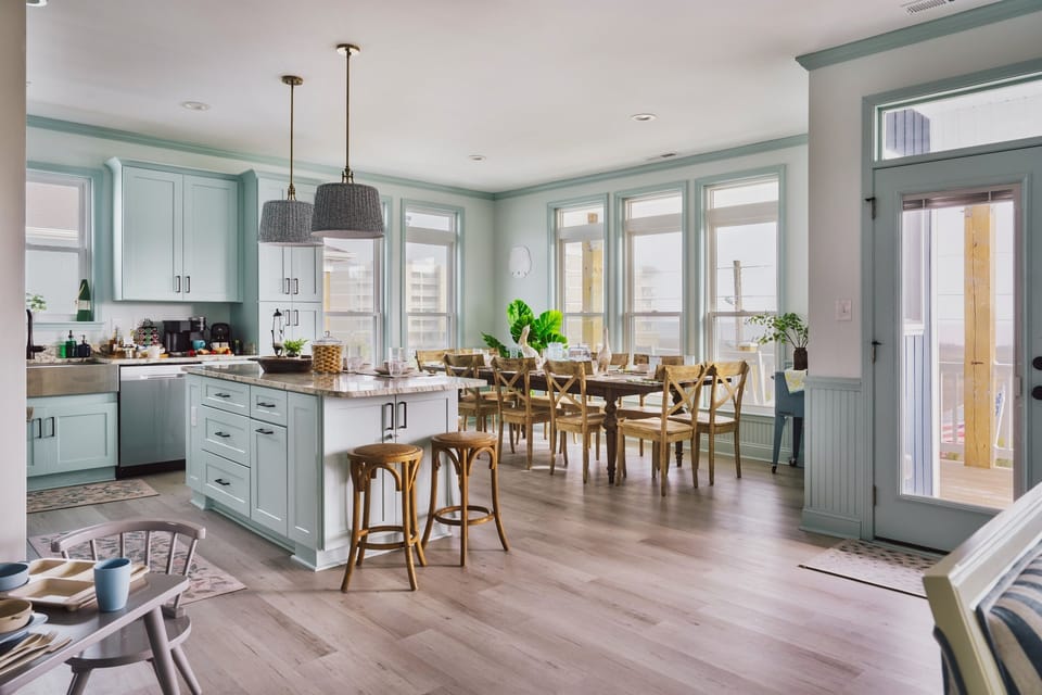 Open kitchen layout, chic dining table, and a stylish bar with stools on the upper level