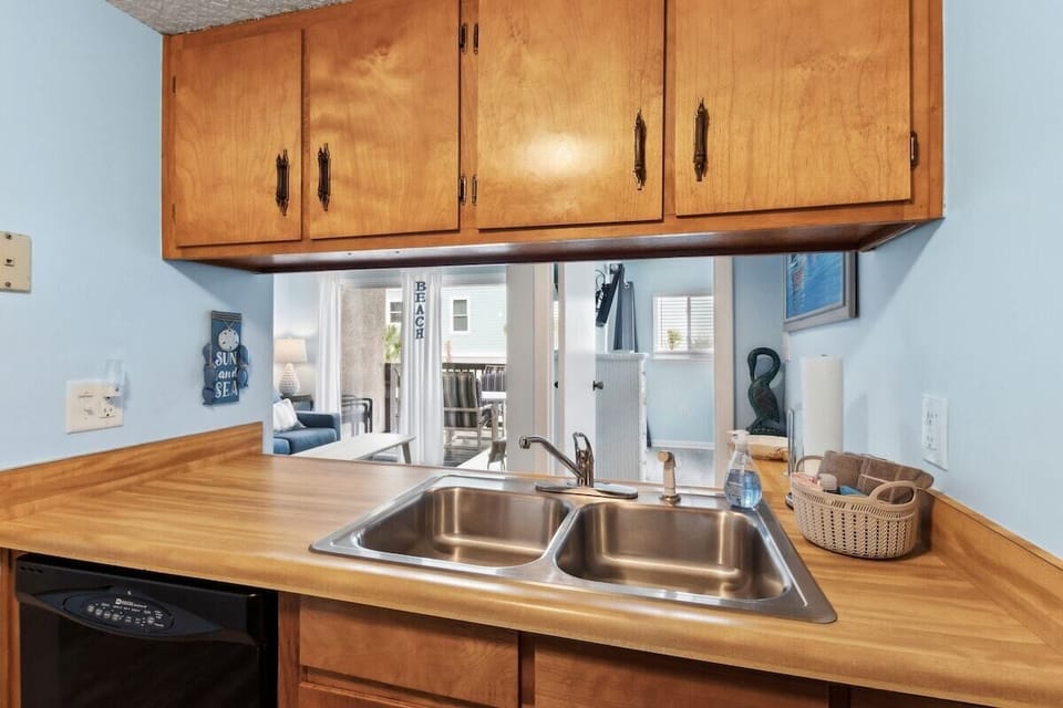 Kitchen prep area with double sink, wood cabinetry, and coastal blue accents.