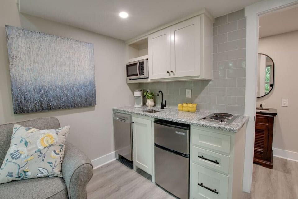 Kitchenette, with stove top, washer, microwave, sink, coffee machine, and mini fridge.