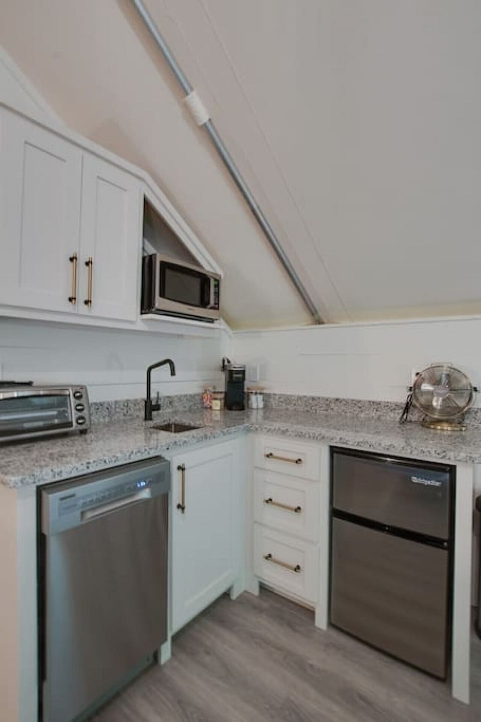 Well-equipped glamping tent with a modern kitchenette, including a dishwasher, fridge, and coffee maker, perfect for enjoying the comforts of home in a nature-filled setting.