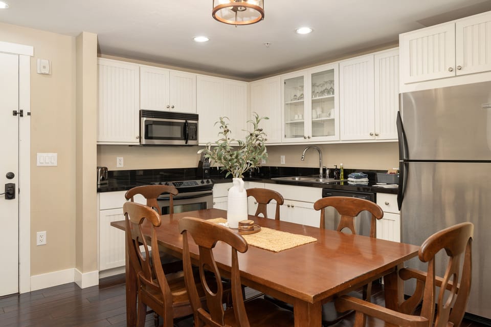 A modern kitchen with white cabinets, black countertops, and stainless steel appliances.