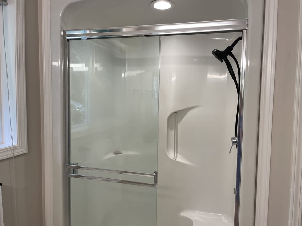 Glass walled walk in shower with a built in seat.  Massage shower head. 