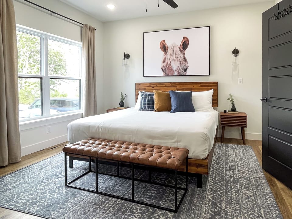 Inviting main level king bedroom with bench seat, night stands, and en suite bathroom