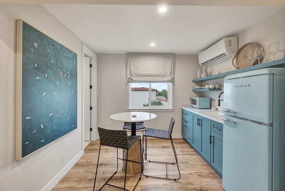 Stylish kitchen corner w/ blue cabinetry, open shelves & wall art adding a creative touch