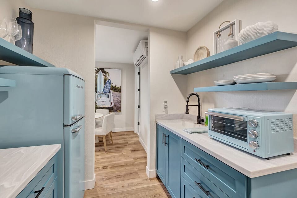 Compact kitchenette w/ retro fridge, open shelves & essentials for easy meal prep