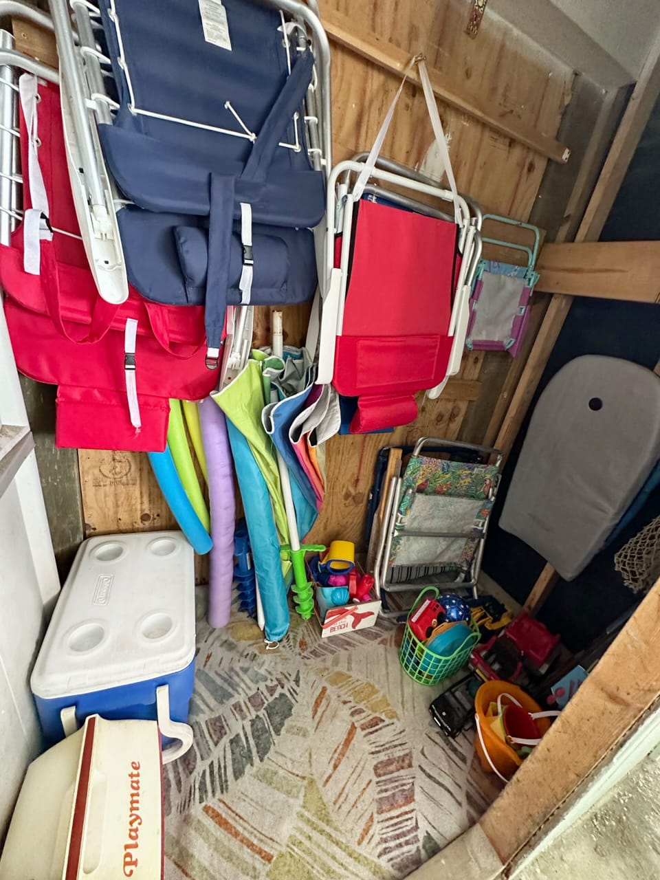 Storage area with beach chairs, 2 beach umbrellas, coolers and toys.