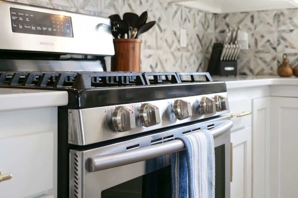 - Close up of stainless steel gas range and oven in kitchen   - Modern appliances ready for cooking family meals with ease   - Contemporary backsplash design adds detail to the kitchen  