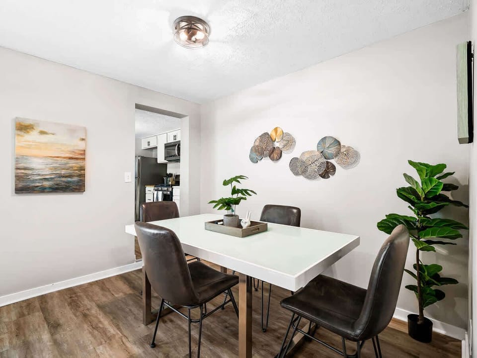Gather around this chic glass-top table surrounded by modern art and greenery—perfect for meals, games, or catching up over coffee! ☕️