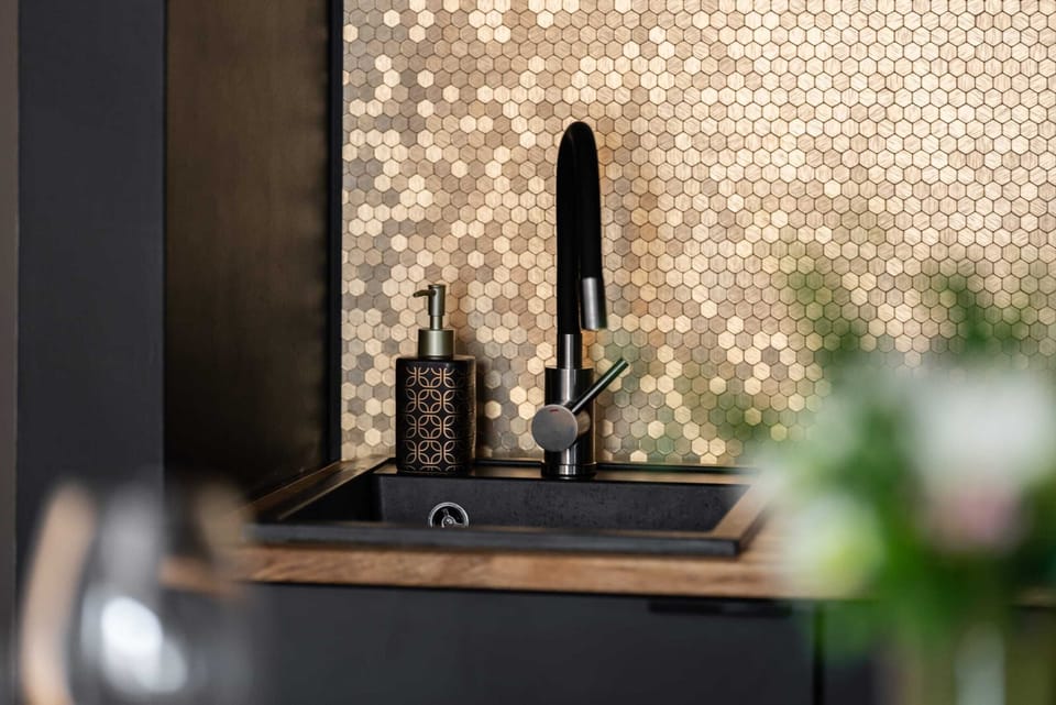 A sleek black-and-wood kitchen paired with a cozy dining area, illuminated by stylish pendant lights.