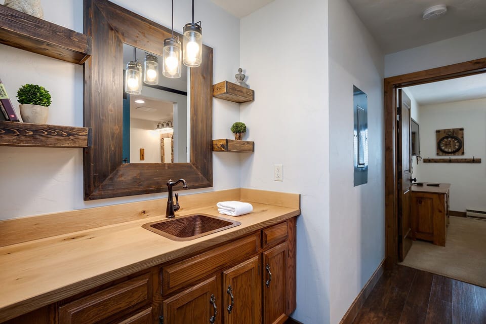 Rustic charm meets modern comfort in your bathroom, featuring rich wood cabinetry, mason jar lighting, and thoughtful touches that create a warm, welcoming retreat.