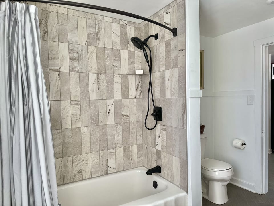 Natural tile to the ceiling with hand held shower brings a delightful washing. 