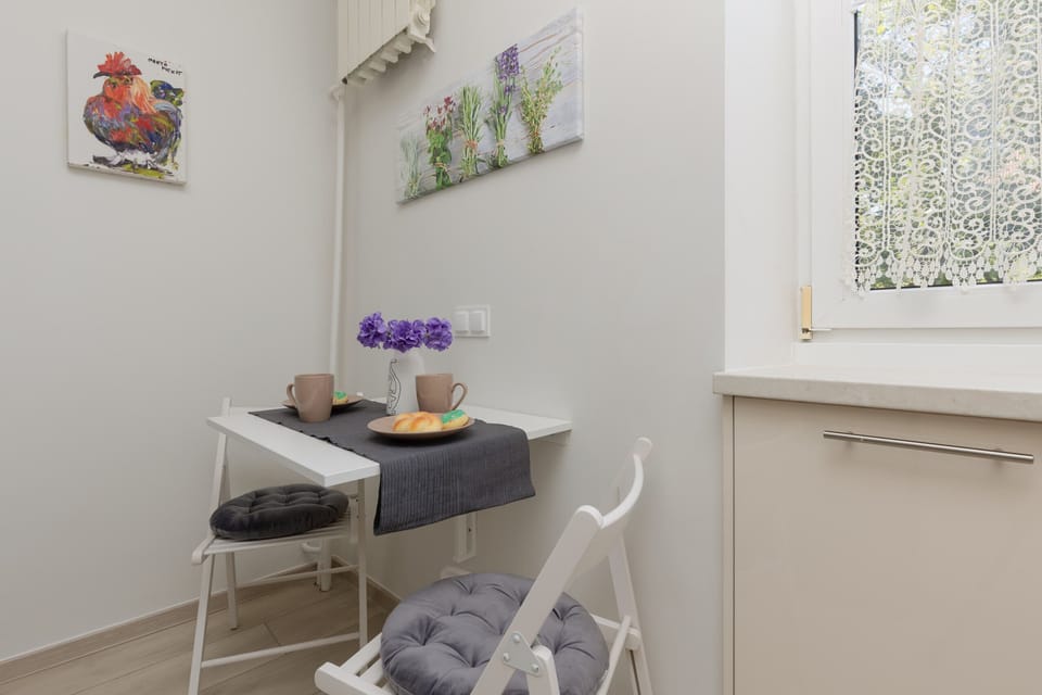 A well-lit dining area with a small table set for two, placed next to a fully equipped kitchen.