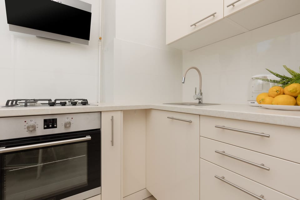A compact kitchen with white cabinetry, a gas stove, and a stainless steel sink, offering a functional design.