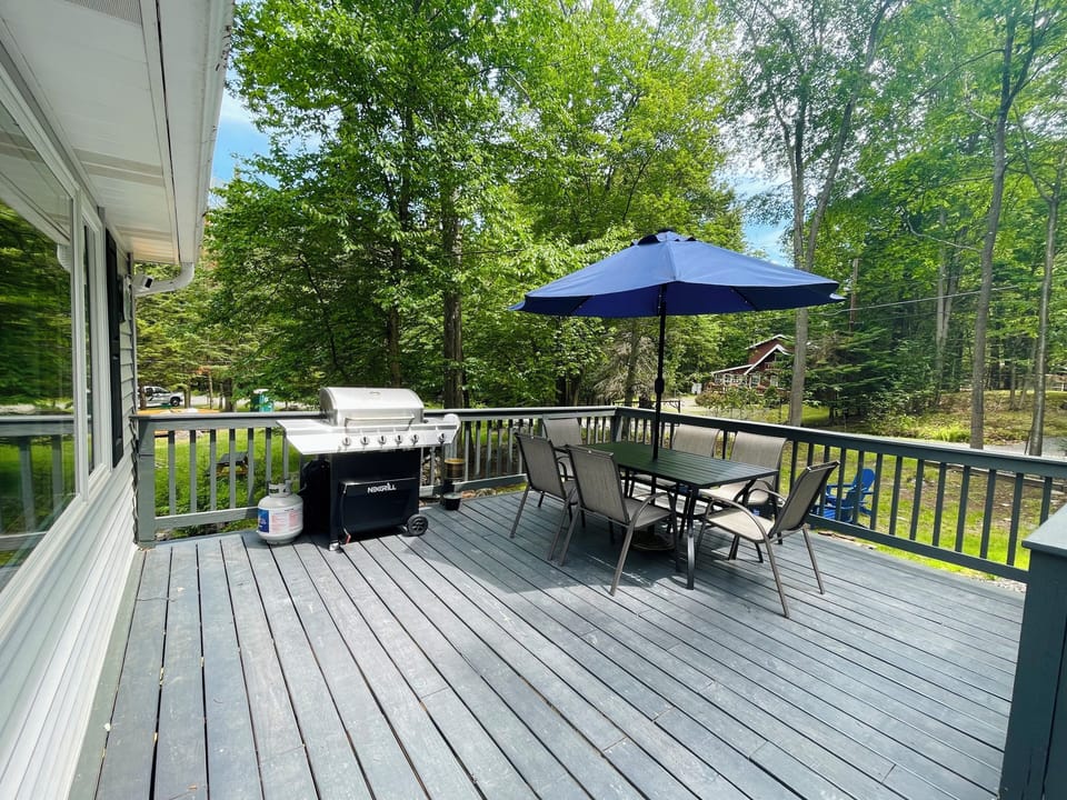 Front porch with a table set for six people and gas grill.