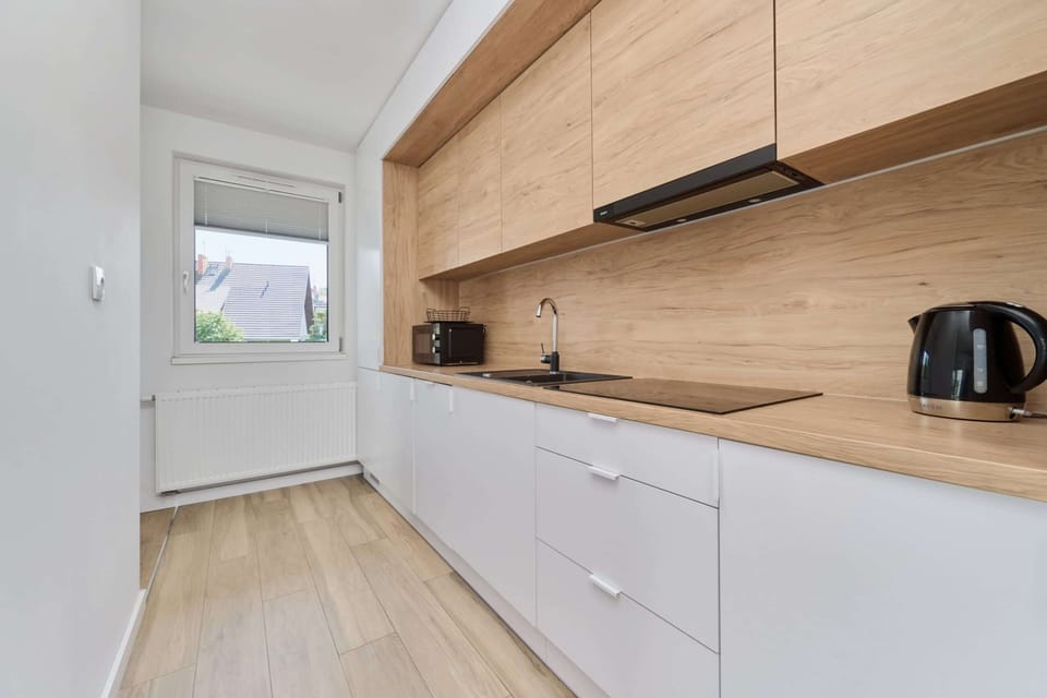 A sleek kitchen with wooden countertops, white cabinets, and all necessary appliances.