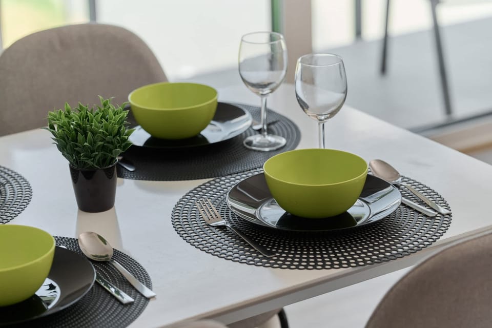 A beautifully set dining table with modern tableware, ready for a meal.