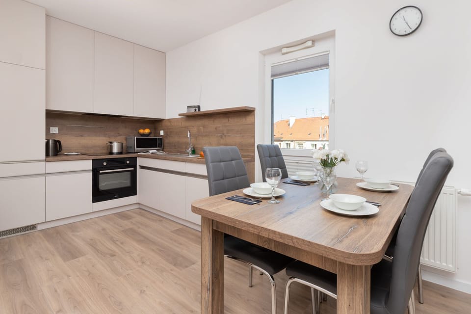 A combined living and dining area featuring a TV, dining table for two, and natural wooden furniture.