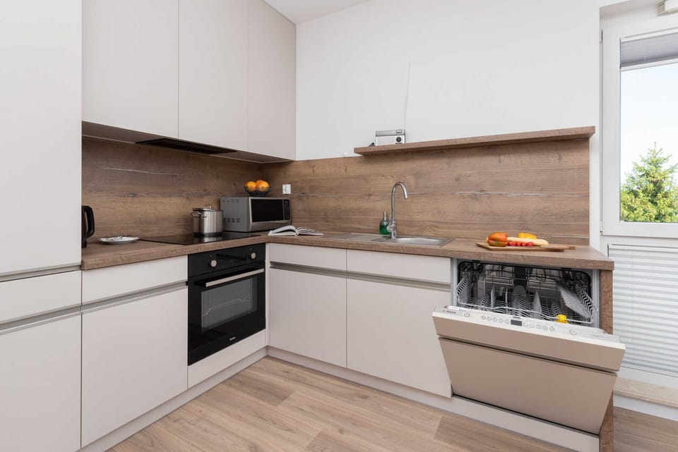A sleek kitchen with white cabinets, wooden countertops, and modern appliances.