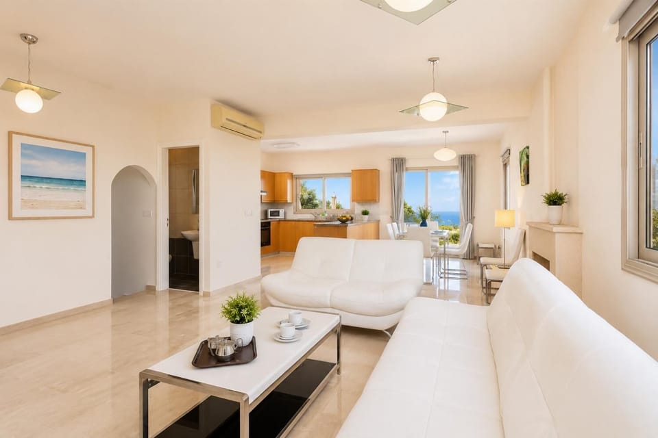 Open-plan living room with sofas, dining area, kitchen, ornamental fireplace, A/C, WiFi internet, and satellite TV