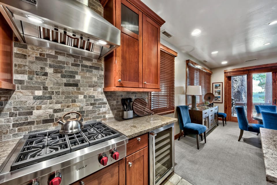 Stone tile backsplash highlights the stainless steel range and granite counters in the kitchen.