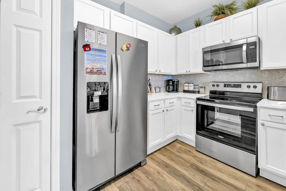 Another kitchen angle highlighting full-size fridge, modern appliances, & smart storage