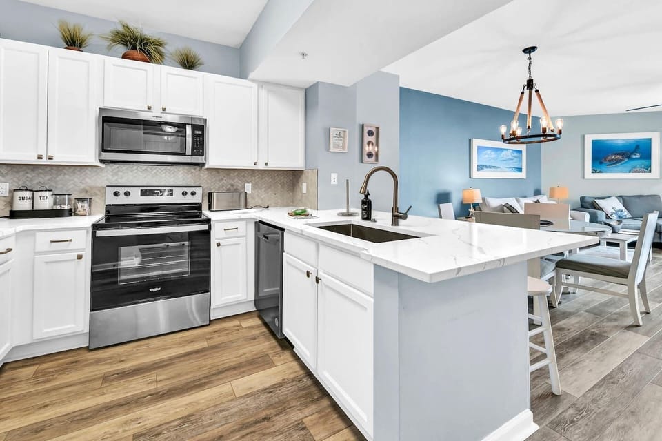 Modern kitchen w/ white cabinetry, island seating, & full-size appliances for easy meals
