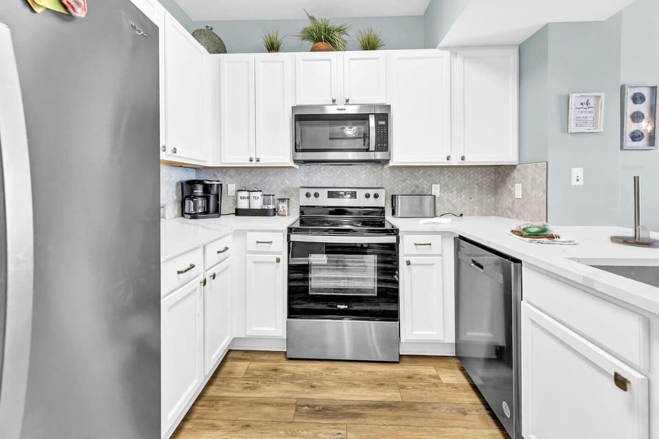 Bright, full kitchen w/ stainless appliances, ample counter space, & clean white cabinetry