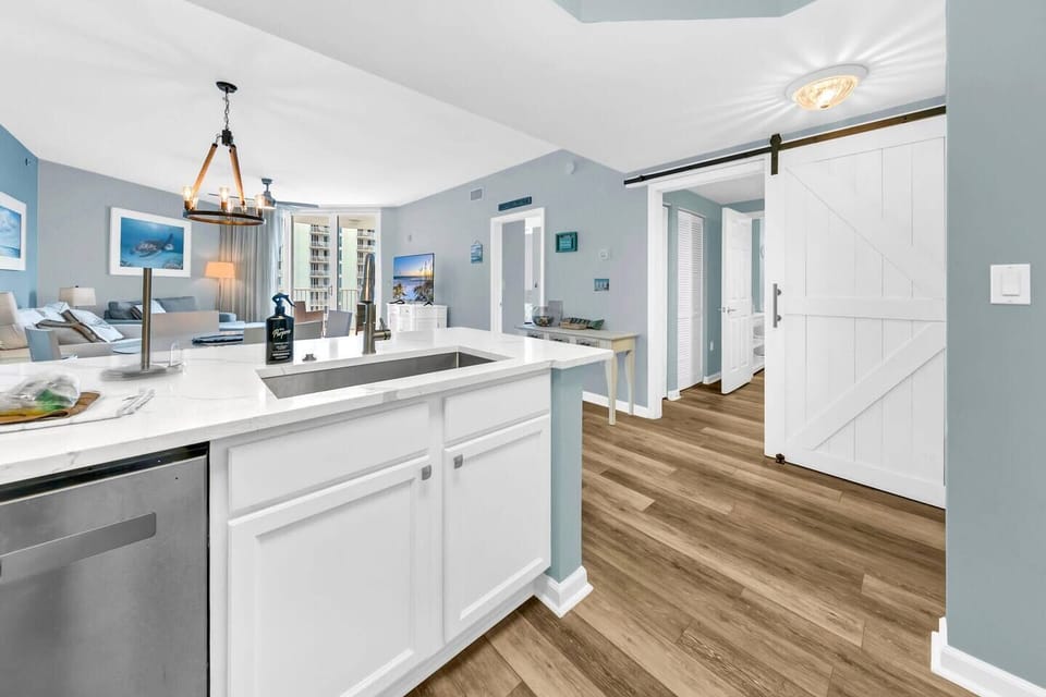 Open kitchen view flowing into the living space, w/ warm floors & a charming sliding barn door